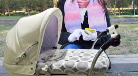 woman connected to social networks with a stroller at a park in winter