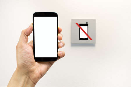 hand on a no mobile phones sign isolated in wall background.All screen content is designed by us and not copyrighted by others and created with digitizing tablet and image editorの写真素材