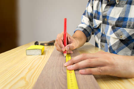Shot of a handsome young carpenter measuring a piece of woodの写真素材