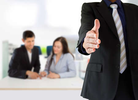 people giving welcoming to the corporate with two persons in the background at the office. The man giving wellcome and the man who is in the meeting is the same person.の写真素材