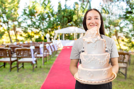 woman confectioner is holding the bridal cake at the wedding placeの写真素材