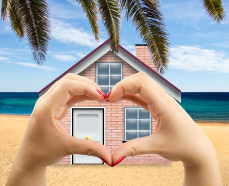 woman making the heart shape with her hands on beach house backgroundの写真素材