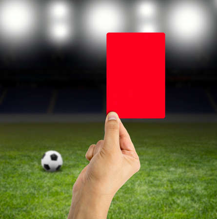 Football referee showing you the red card in a stadium under the bright focusesの写真素材