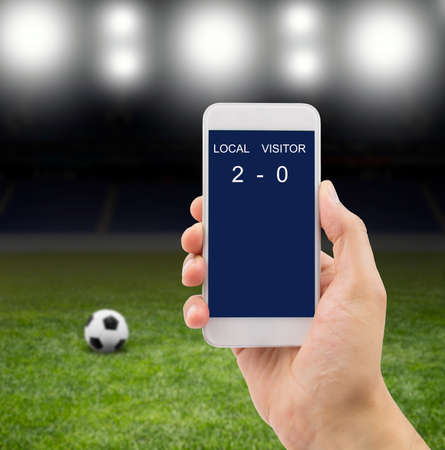 betting man through his smart phone in a stadium under the bright focusesの写真素材