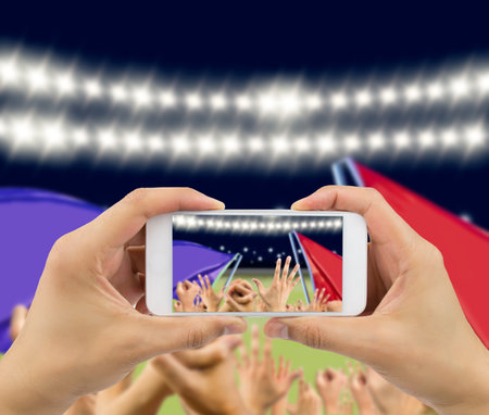 Man photographing his team's victory with a smartphone of the football stadiumの写真素材