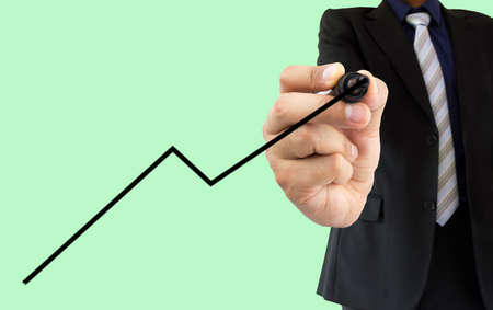 businessman drawing a line graph with felt tip pen on a transparent wipeboard isolated on a green backgroundの写真素材