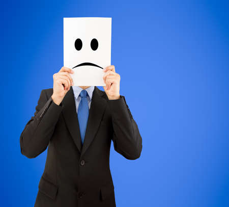 businessman showing a negative emoticon in front of his face on a green backgroundの写真素材