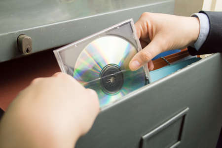businesswoman keeping a backup of documents in a file cd in cabinetの写真素材