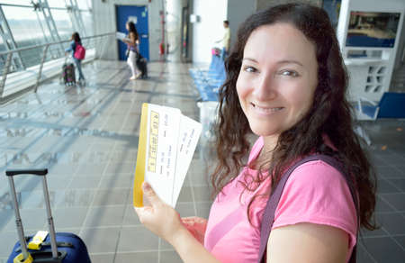 happy woman smiling holding the boarding pass at the lobby airportの写真素材