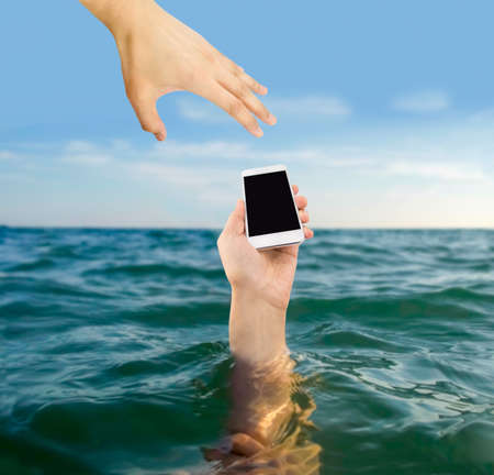 man who rescues the phone of a person who is drowning in the seaの写真素材