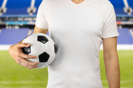 Cropped image of a young man holding a soccer ball under his arms with colors white in Madridの写真素材