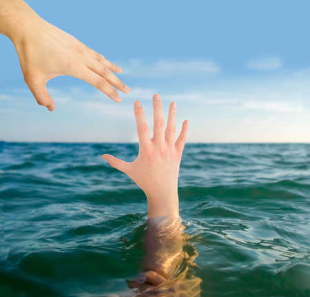 hand man helps a woman drowning in the ocean and rescues her from deathの写真素材