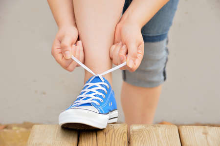 closeup of young woman knotting sneakers on a wooden bench at the parkの写真素材