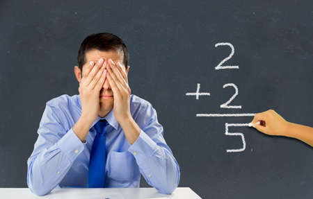 He stressed teacher in a class with a child on the board making a mathematical calculation wrongの写真素材