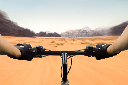 closeup of hands of a mountain biker at high speed on the desert in Jordanの写真素材