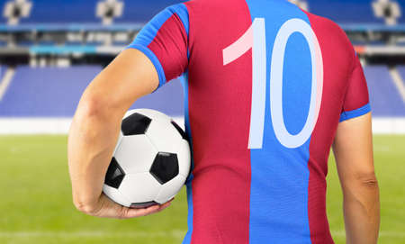 Cropped rearview image of a young man holding a soccer ball under his arms at Madridの写真素材