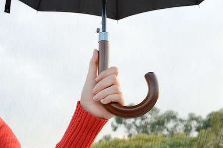 hand of woman holding an umbrella in a cloudy day under the rainの写真素材