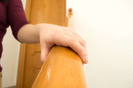 view of front of woman using a railing to go downstairs at homeの写真素材