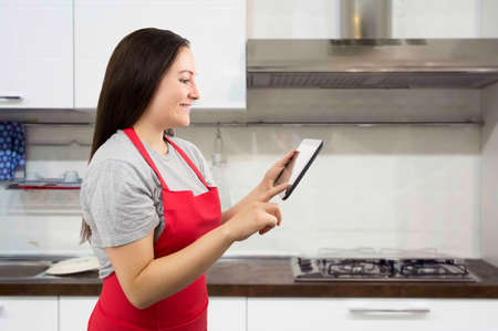 Shot of a woman looking at an online recipe on her digital tablet while she prepares the menuの写真素材