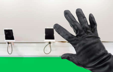 Closeup of a hand of a thief stealing a phone in a storeの写真素材