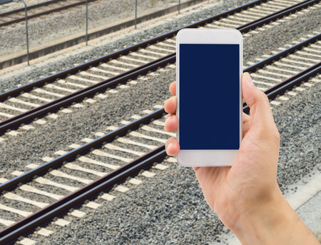 hand holding the phone to searching information of the train with the smartphone at the platformの写真素材