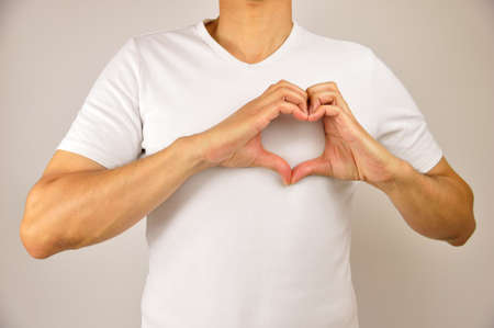 cropped of a man making a  heart shape with his hands on her breast as healthy life conceptの写真素材