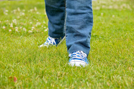 cropped view of a girl walking over the grass at the park with sneakersの写真素材