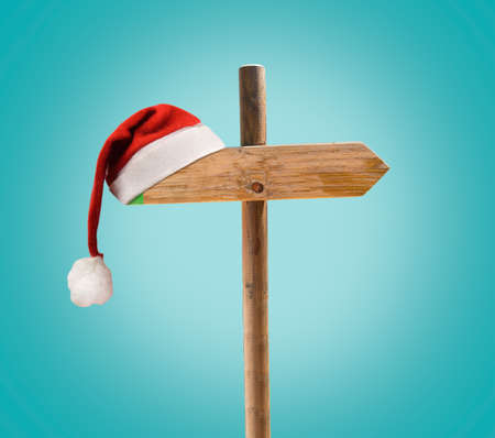 one wooden signpost with copyspace at Christmas with santa hat and green backgroundの写真素材