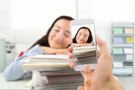 Man photographing an administrative employee asleep on the job to capture the moment and sending to...