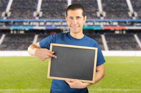 coach of a sports team holding an empty blackboard at the stadium with copy spaceの写真素材