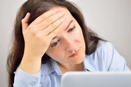 businesswoman experiencing stress at work with a great headache touching her brow with hand and...