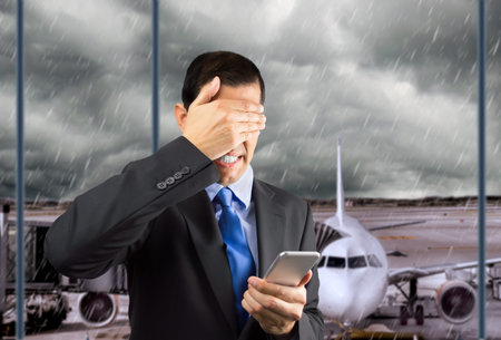 Portrait of an businessman covering his eyes at lobby airport because he not want to look the phone...