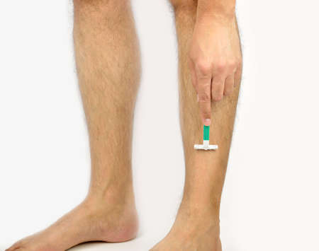 Cropped shot of a man shaving his legs against a white backgroundの写真素材