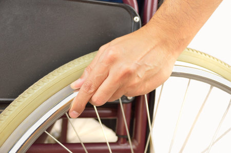 cropped of hand of a wheelchair man pushing it with a white background