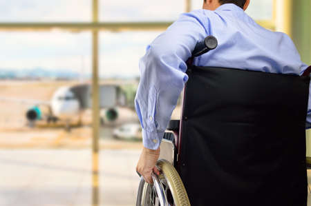 rear view of a business man in wheelchair at the airport with focus on handの写真素材