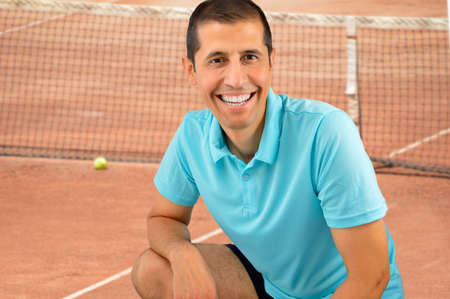 portrait of sportman smiling with joyful toothy smile crouched at a tennis courtの写真素材