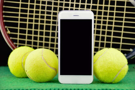 closeup of tennis racket and three ball over the tennis court and smart phoneの写真素材