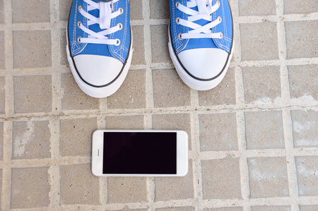 high angle view of a young man finding a phone on the street with sneakers and the phone next at the...