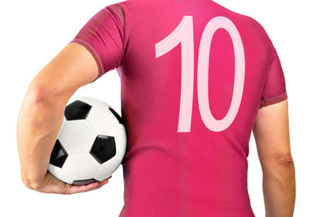 cropped rear view image of a young football player holding the ball under his arms with white background and red tshirtの写真素材