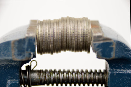 Metal table vise clamp with closed jaws with coins isolated on white background. The concept of...