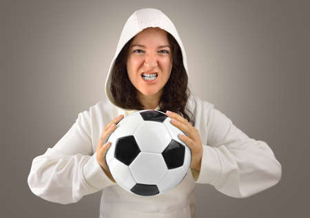 portrait of loser angry and aggressive woman soccer player holding a soccer ball isolated over a  gray backgroundの写真素材