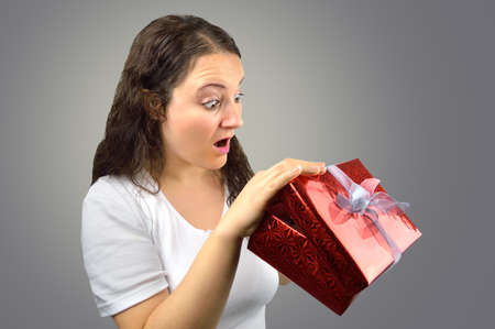 woman opens lid peeks present isolated on a grey backgroundの写真素材