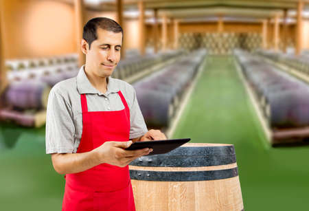 man with apron using a tablet at the wine cellarの写真素材