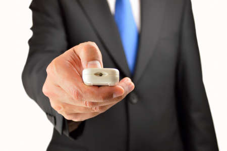 Businessman with a remote controller in his hand and isolated with white backgroundの写真素材