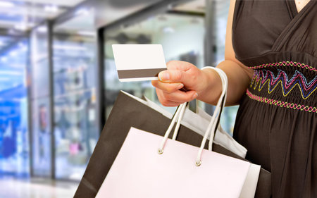 woman holding shopping bags and paying with credit card at the center mall. Concept of a shopaholic