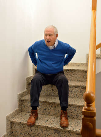 detail of a senior man with backache because of falling on stairs of homeの写真素材