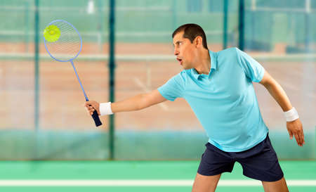 man badminton player standing and swatting the ballの写真素材
