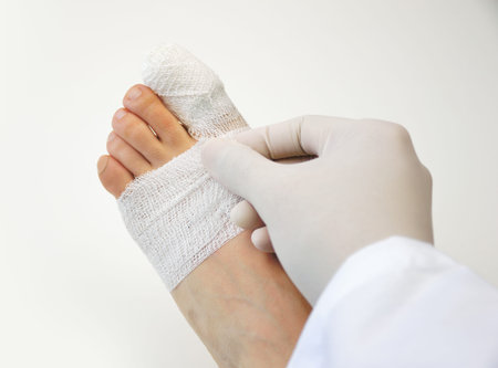 closeup of doctor hand tying bandage on the foot of patient at the clinicの写真素材
