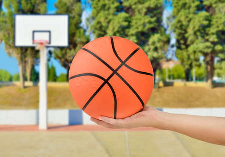Cropped image of a man hand holding a basketball against at oudoorsの写真素材