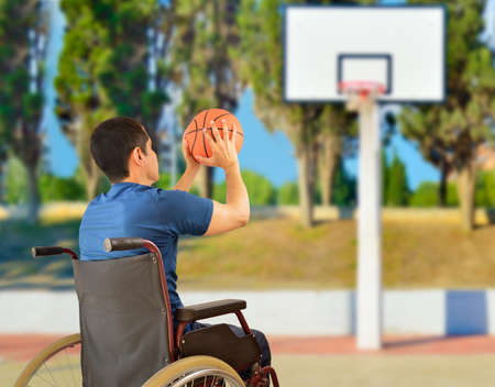 rear view of a basketball player in free throw pose in wheelchair at outdoorsの写真素材